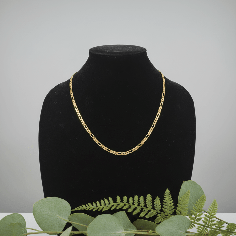 14ct Gold 24" 61cm 5mm 31 Figaro Link Chain displayed on a jewelry stand with green foliage.