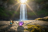 Amethyst heart pendant with butterfly on rock by waterfall