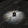 Black gemstone stud on rock with sparkle