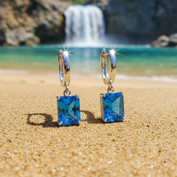 Blue Earrings Laying on Sand by Waterfall