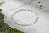 Complete Italian sterling silver figaro bracelet on marble with water drops, butterfly and greenery