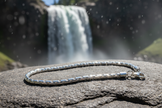 Complete sterling silver figaro chain bracelet near waterfall with sparkle