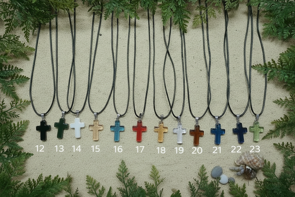 Cross pendants on sand with greenery