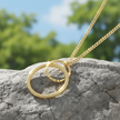 Double circle gold pendant on rock with natural sunlight