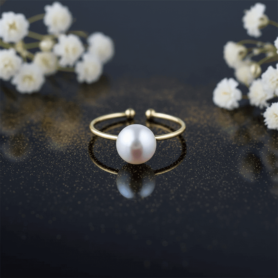 elegant freshwater pearl adjustable ring on a dark surface with small flowers in the background