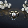 elegant freshwater pearl adjustable ring on a dark surface with small flowers in the background