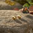 Gold ball earrings with butterfly on background rock