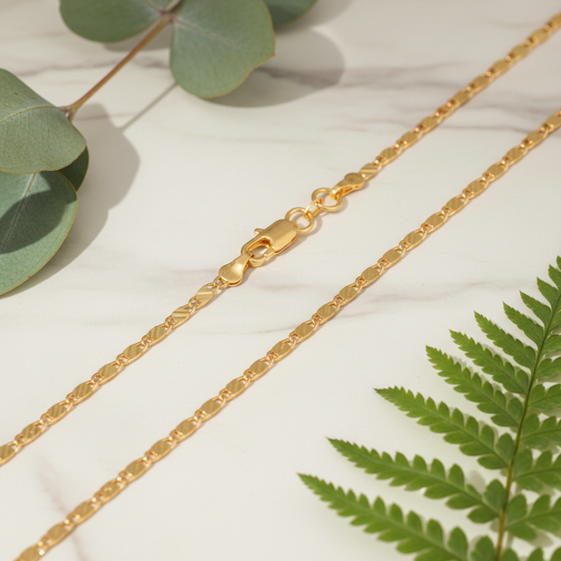 Gold Chain Detail on Marble with Greenery