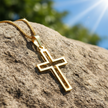 Gold cross pendant with complete chain on rock
