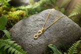 Gold infinity necklace with lizard peeking from behind rock