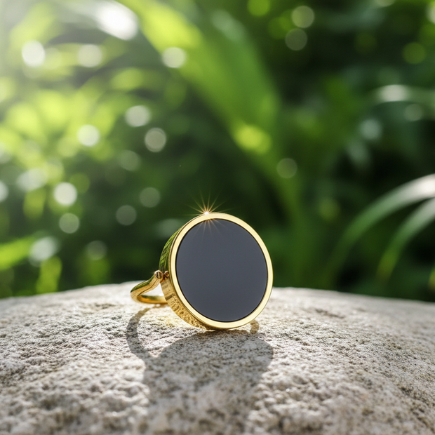 Gold ring with black onyx on natural rock with green background