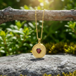Gold sunburst ruby pendant hanging from branch on rock with enhanced sparkle