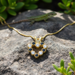 Heart pendant with gold snake chain on natural rock