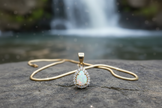 Image 4 - Diamond halo pendant laying flat with gold snake chain