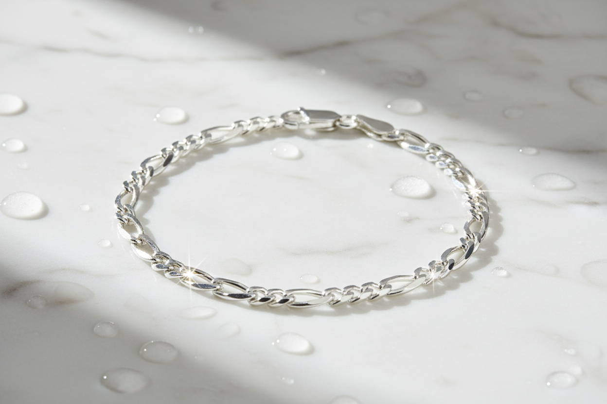 Italian sterling silver figaro chain bracelet on marble with water drops