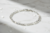 Italian sterling silver figaro chain bracelet on marble with water drops