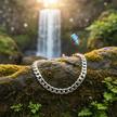 Silver chain bracelet on rock by waterfall with butterfly
