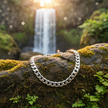 Silver chain bracelet on rock by waterfall
