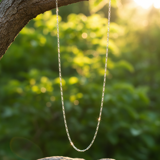 Silver chain hanging from branch over rock