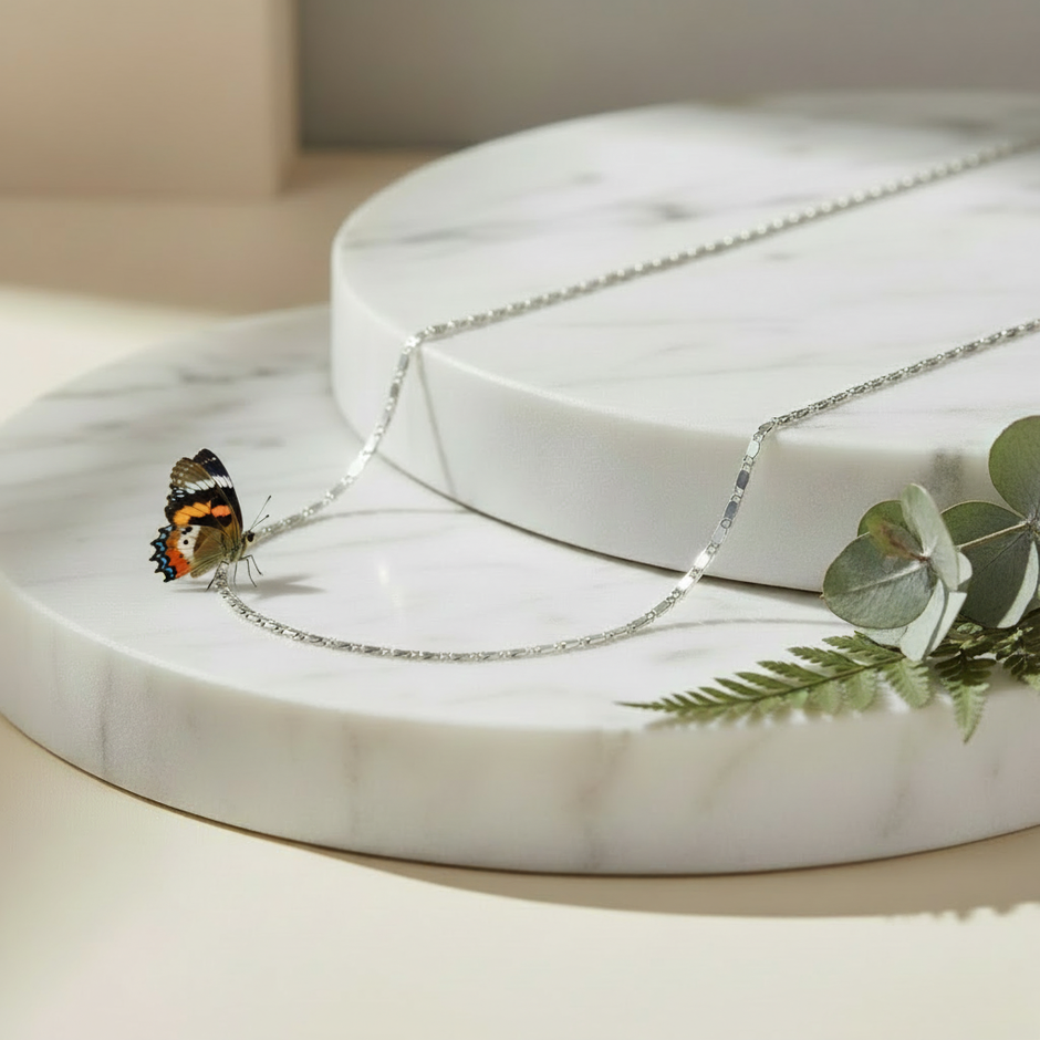 Silver Chain on Marble with Greenery and Butterfly