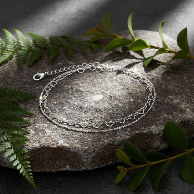 Silver double-strand anklet on rock with sparkle and greenery