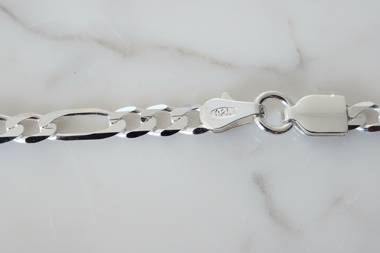Sterling silver figaro chain bracelet clasp on natural stone background
