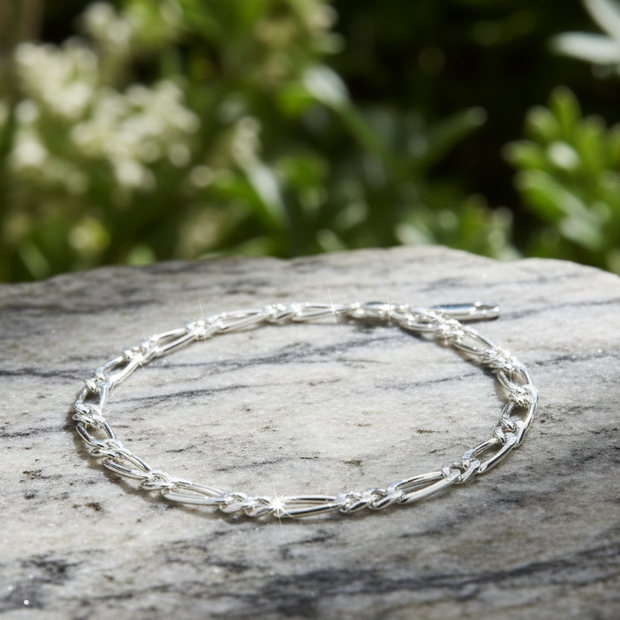 Sterling silver figaro chain bracelet on marble rock in natural environment