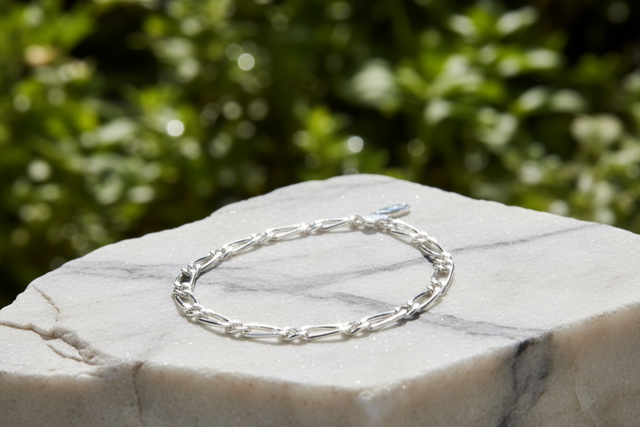 Sterling silver figaro chain bracelet on marble rock in natural setting