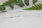 Sterling silver figaro chain bracelet with greenery on marble background