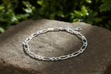 Sterling silver figaro chain bracelet with intense sparkle on natural rock