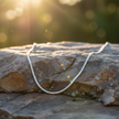 Sterling silver snake chain on rock with sunlight